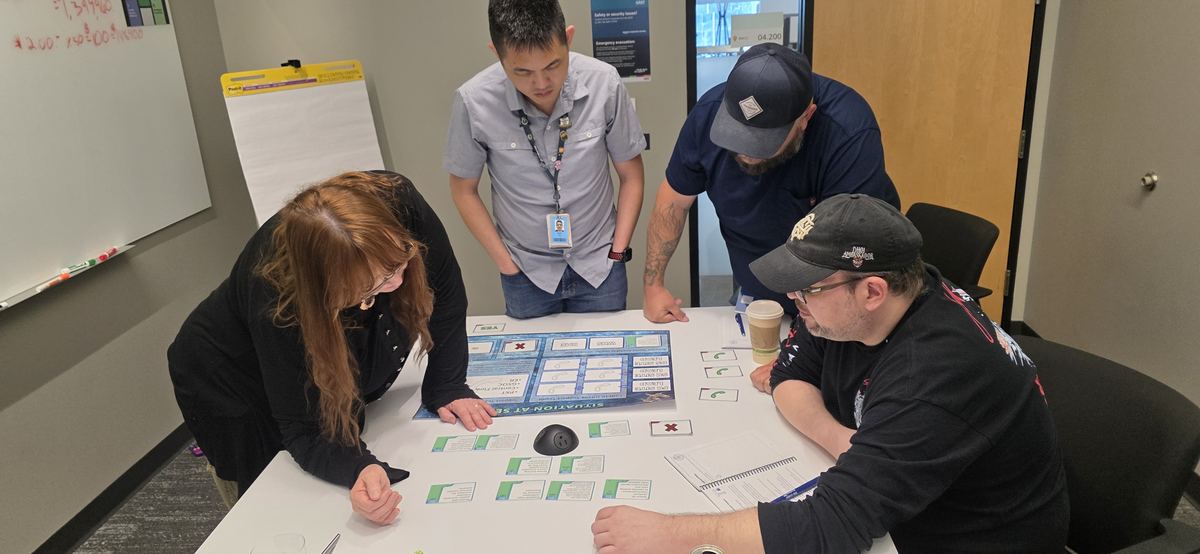 Four leaders around a table working through the simulation's board game and decision cards